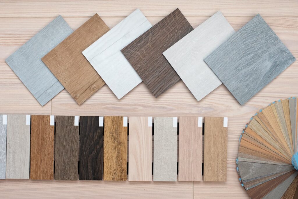 A flat lay of outdoor flooring samples in square tile and plank formats, featuring grey, brown, white, and natural wood-tone finishes - FloorXpert