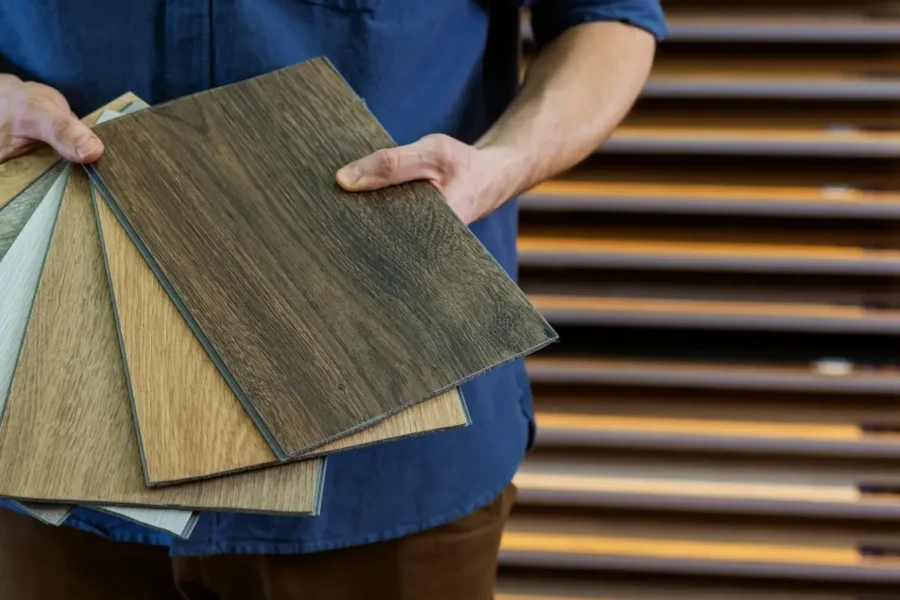 A flooring specialist holding a selection of wood-look vinyl flooring samples in various tones and grain patterns at a showroom - FloorXpert